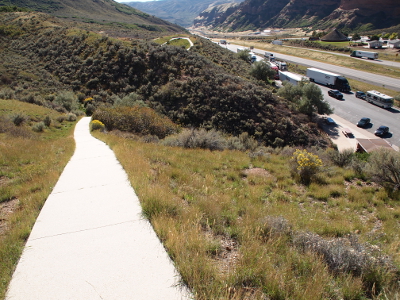 [The walkway disappears out of view midway through the image where it drops into the canyon. The rest stop and road are seen over the hillside on the right.]